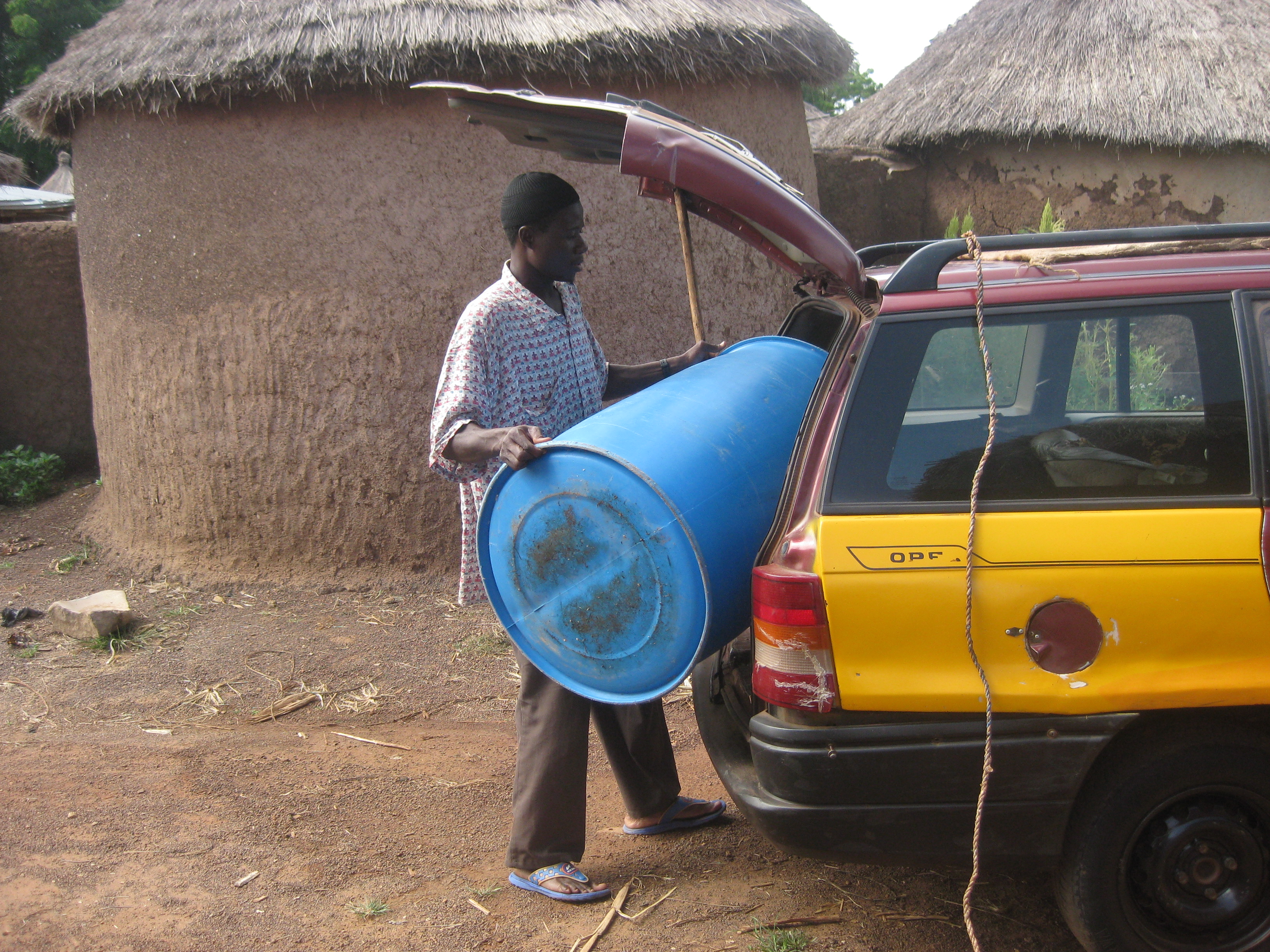 Loading a blue tub into the trunk outside of Fati's house
